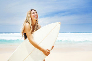 Women on beach holding surfboard.