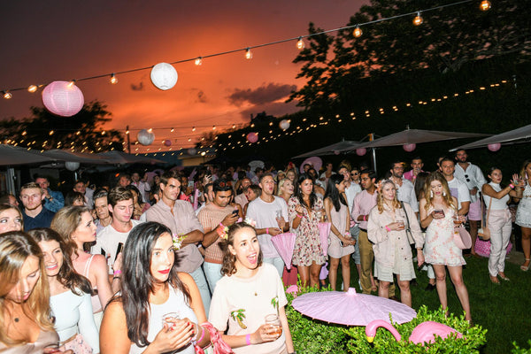 Party goers at sunset under pink lanterns