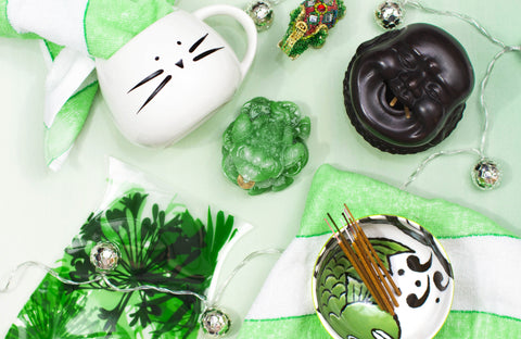 Arrangement of Ruby's purchases, including white cat mug, green and white sauce dish, green frog, Buddha head incense holder, and more