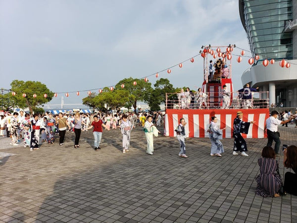 Line of festive bon odori dancers in traditional Japanese clothing at a bon festival