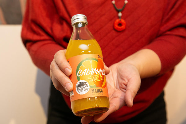 Person holding bottle of Brooklyn Crafted mango calamansi aid