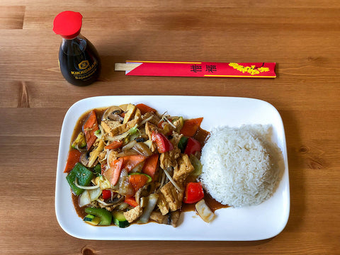 A chop suey dish with rice, chopsticks, and soy sauce