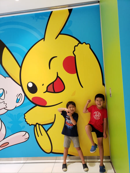 Two boys having fun in front of a Pikachu mural