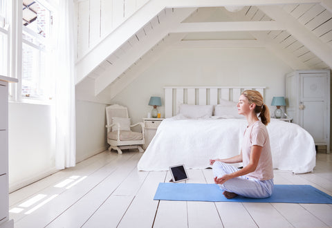 Girl doing yoga on blue yoga mat in white bedroom