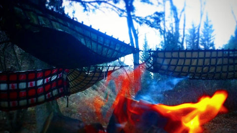 Multimok hammocks in a wagon wheel configuration near a campfire