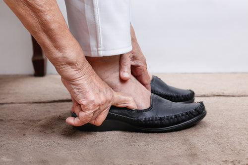 elderly woman putting on slip on shoes