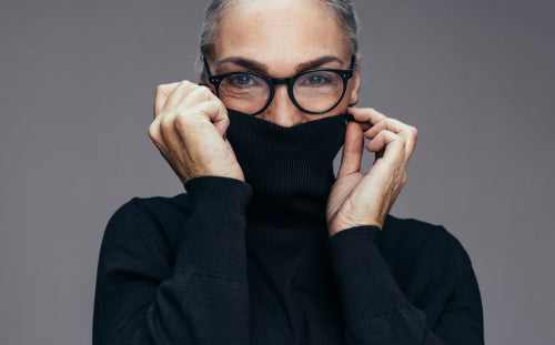 senior woman covering face with turtleneck