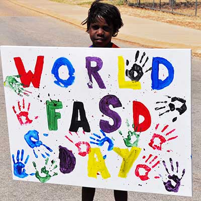 Young boy holding World FASD Day sign