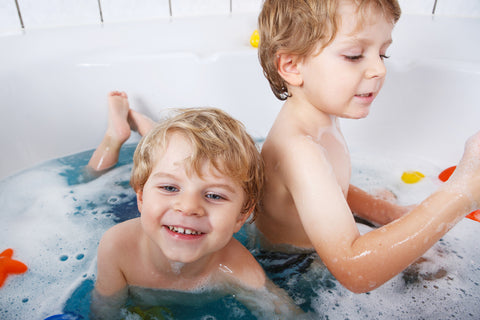Siblings playing with bath toys during bath time