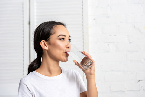 woman drinking water to hydrate herself