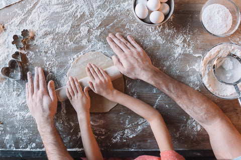 hands of family rolling dough together