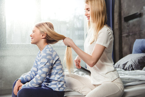 mom showing daughter how to detangle hair