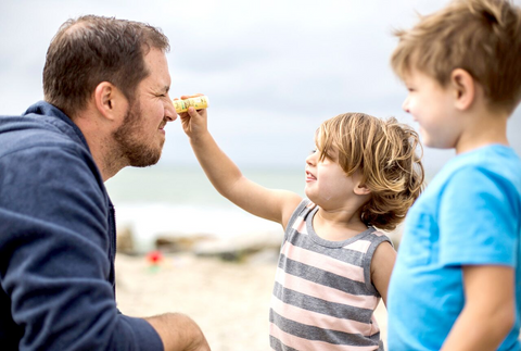 kid applying coral reef safe sunscreen on dad