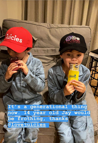 Two boys in Juicies caps eating Juicies