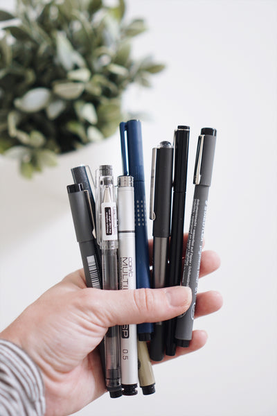 Best Pens + Adhesives for Journaling, adhesive dots, pens in hand