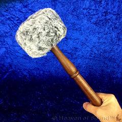 hand holding handle of a gong striker crystal point end blue background