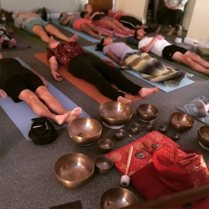 group of people lying on a mat many singing bowls placed on the front of the room