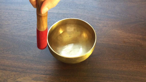 hand holding wooden mallet with red suede cover circling on a Shanti Bowl tiny singing bowl