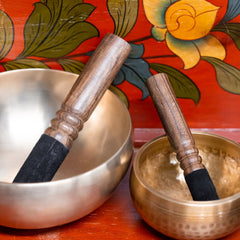 two singing bowls different sizes mallets with black suede cover inside