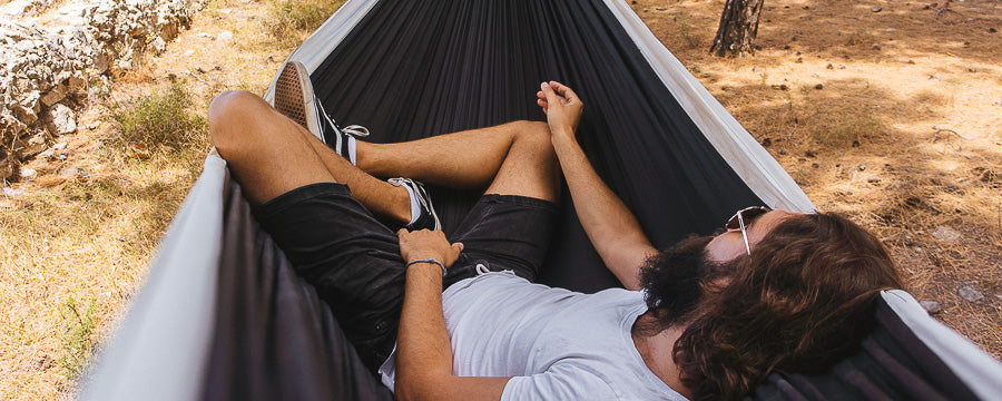 A man lies diagonally in a parachute silk hammock