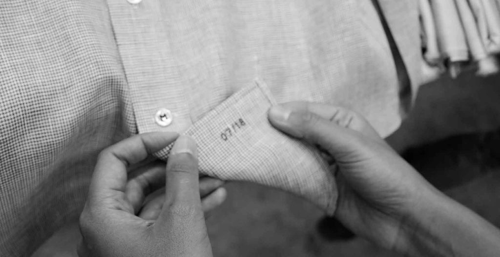 tailor showing stitching of men's custom made-to-measure dress shirt