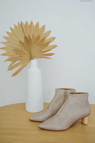 The Coclico Whoop Bootie in Guanto Cloud on a wooden table with decor in background. 