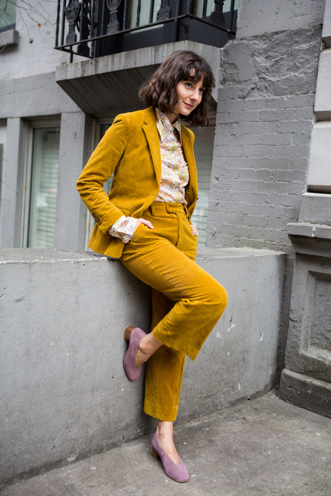 Full-body shot of Alyssa Coscarelli leaning on a concrete wall with hands in pockets.