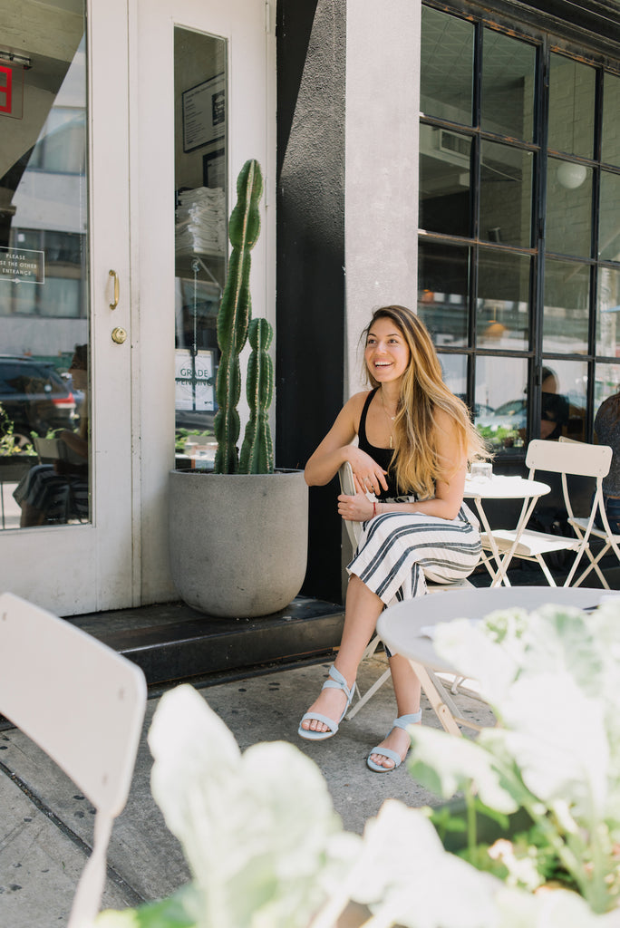 Adriana Urbina seated cross legged outside in her Coclico Float Sandal in Dew Suede.