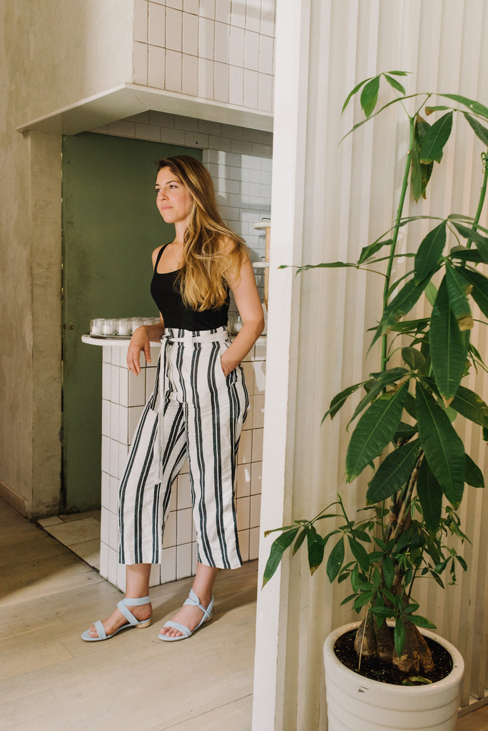 Full-body shot of Adriana Urbina leaning against a counter in the Float Sandal in Dew Suede.