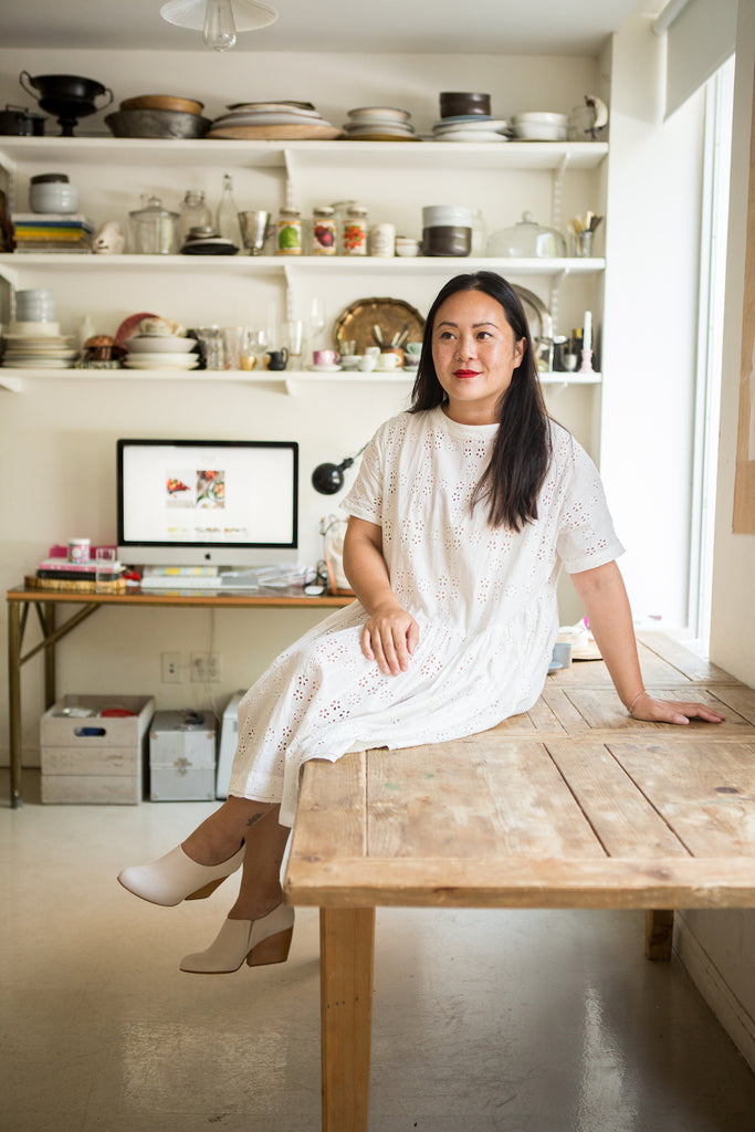 Diana Yen sitting on a wooden table in her food styling and consulting studio in the Lower East Side.