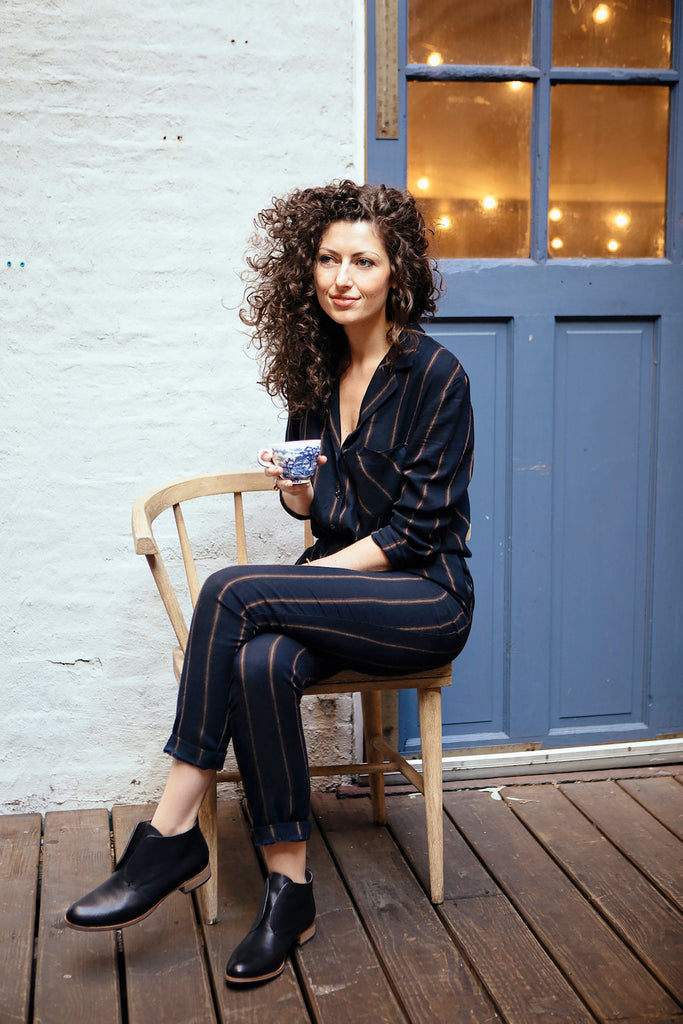 Elisa Marshall seated cross legged with a mug in hand. 