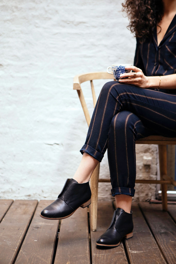 Elisa Marshall sitting with legs crossed holding a mug. 