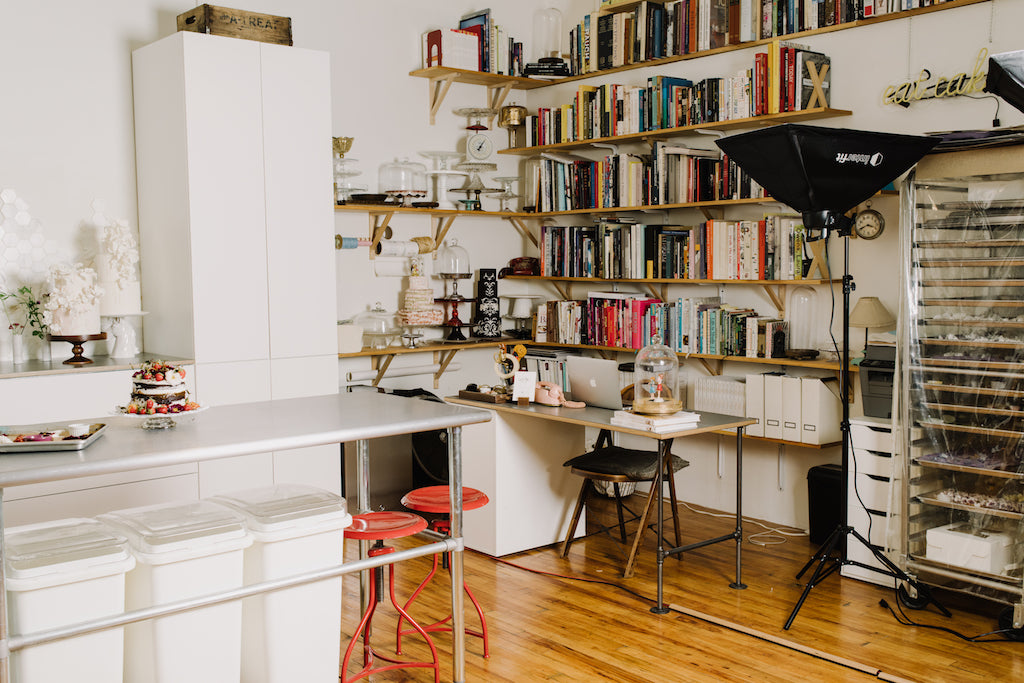 Image of Emily Aumiller's work space - kitchen on one side & desk and bookshelves on the other. 