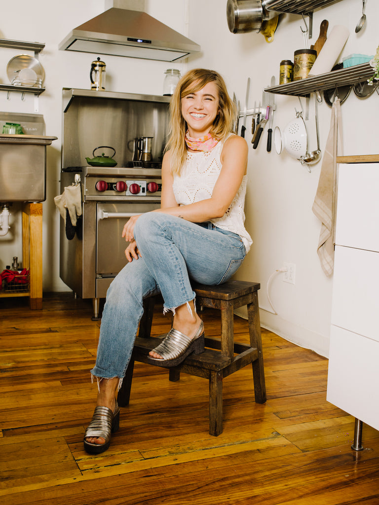 Emily Aumiller seated on a wooden step stool in a kitchen. 