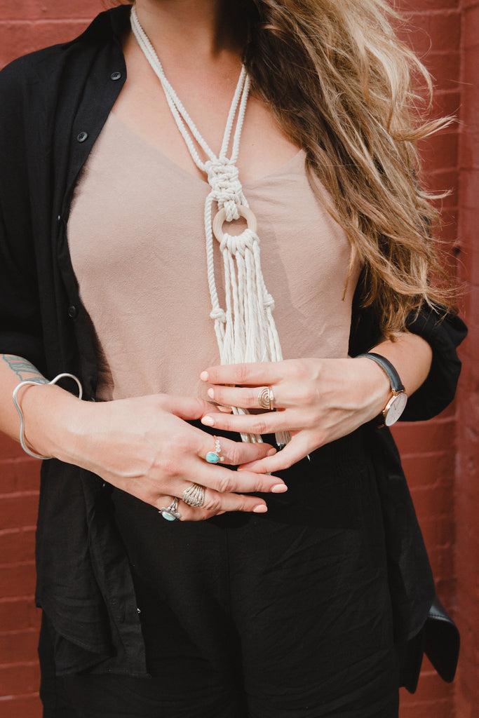 Close up of Emily Katz, owner of Modern Macramé, holding her macrame necklace. 