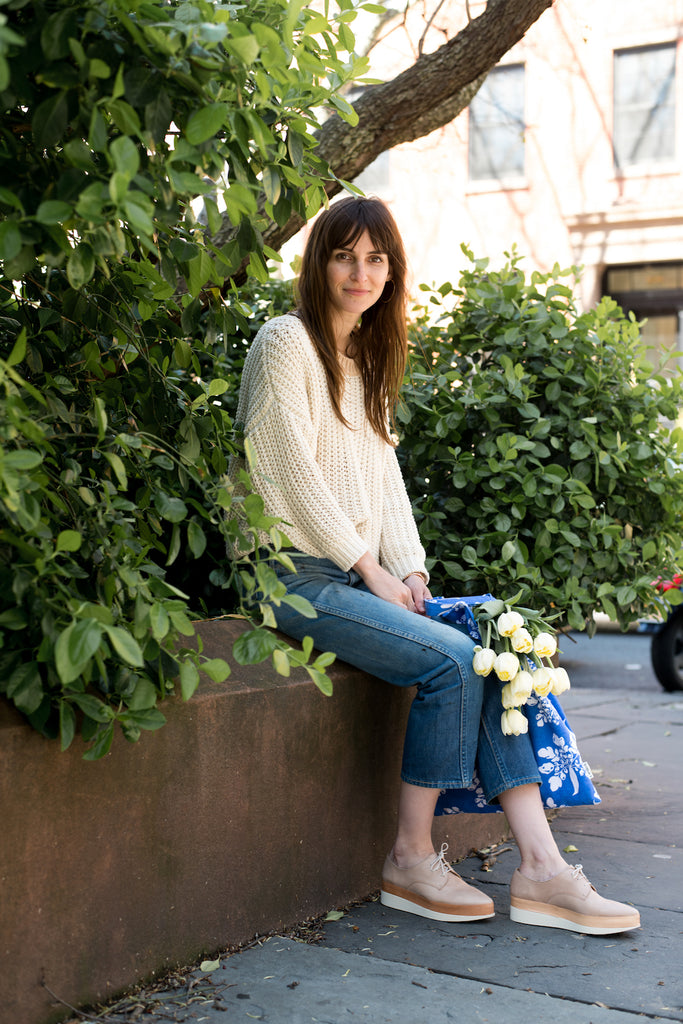 Brooklyn-based lifestyle blogger and author, Erin Boyle seated outdoors surrounded by greenery.