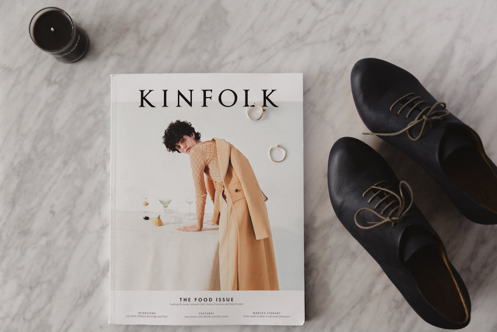 A Kinfolk book displayed on a marble table alongside a pair of Coclico Bea oxford shoes and decor.