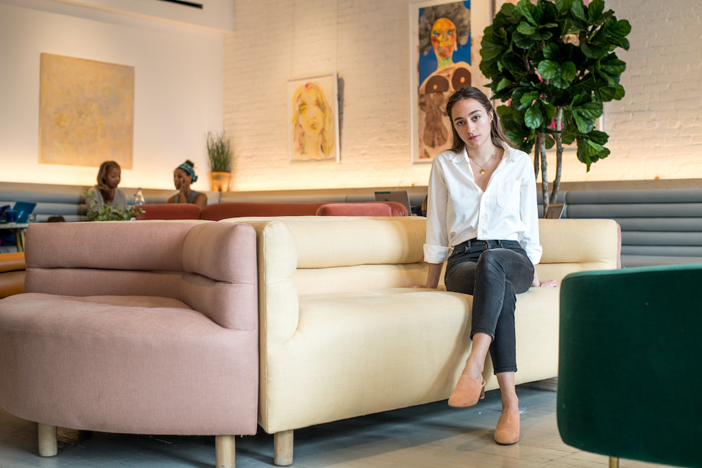 Paris-born, New York-based art consultant Lolita Cros seated cross legged on a couch.