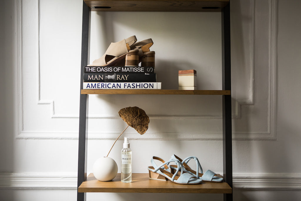 Close up image of two shelves with Coclico sandals on display along with the Jak Snow Magic Spray & other decor.  