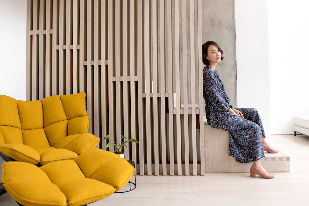 Sun Sinawi seated on wooden staircase in her Coclico heels. 