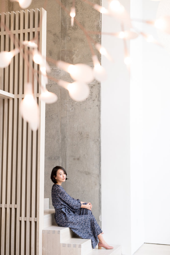 Sun Sinawi, shop owner of Pas Mal and all-around advocate for independent design seated on wooden steps. 