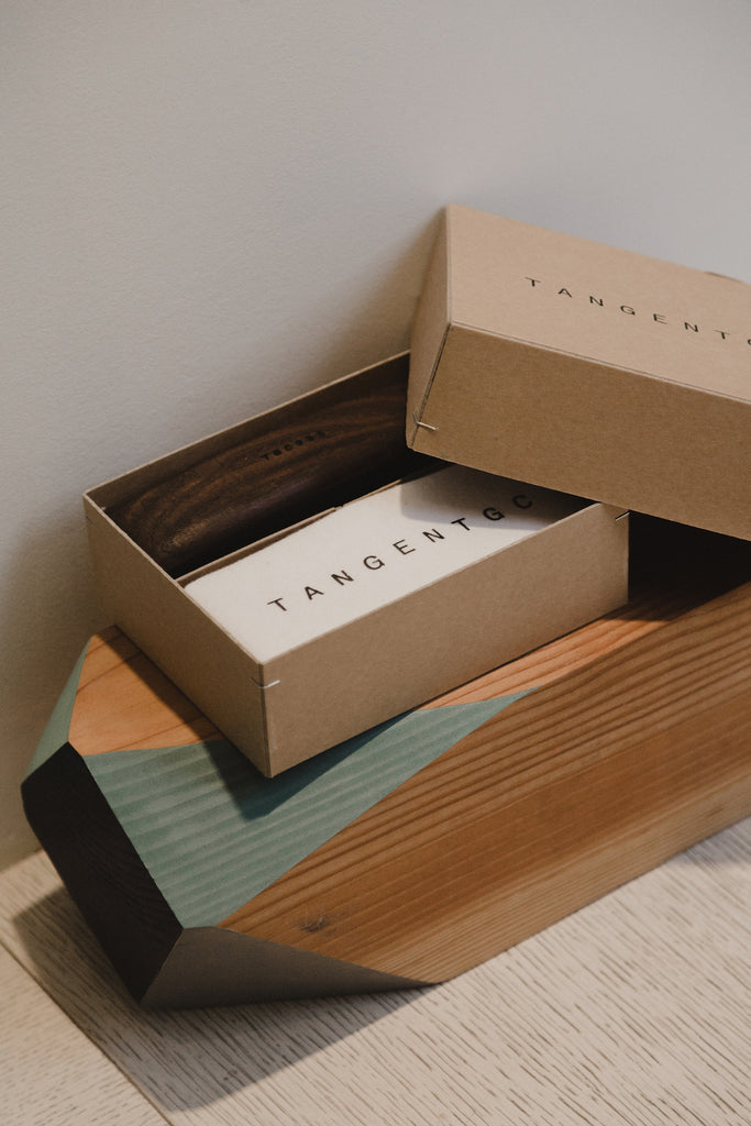 Close up of the Tangent GC box placed on a solid angled wood block decor.