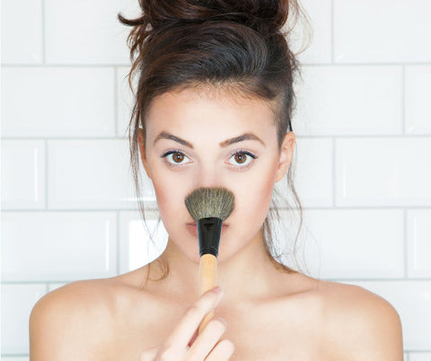 young girl with makeup brush to face