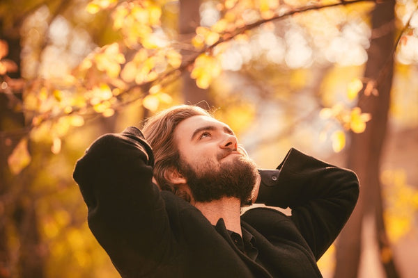 Portrait of young handsome bearded guy in the autumn city park. Autumn style
