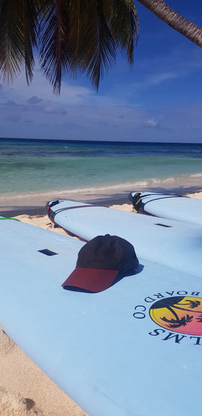 Green wax sports cap lying on surf board on a beach