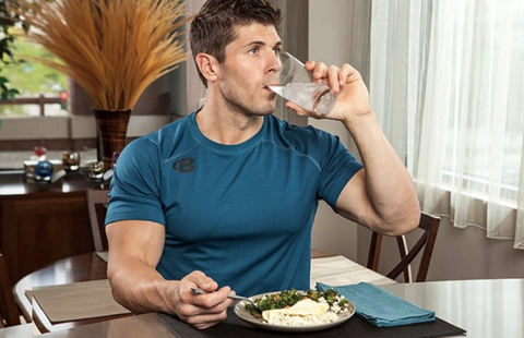 A man sitting by the dining table and drinking water