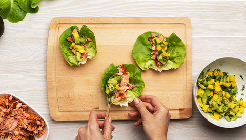 Placing salmon and avocado mixture into lettuce wraps