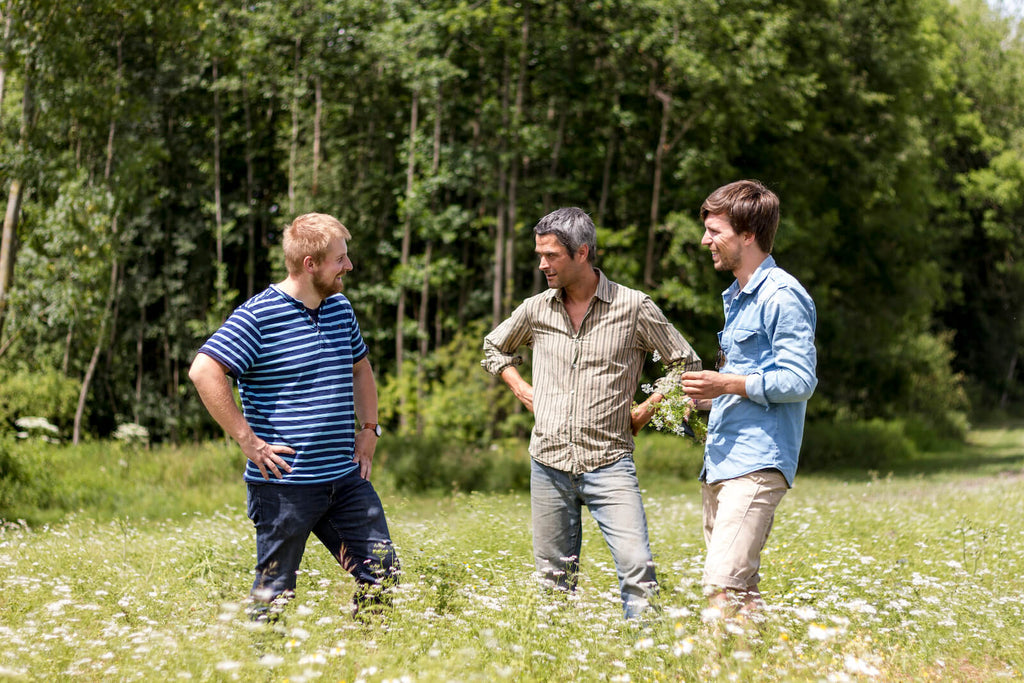 Gründer Richard Friedrich und zwei Mitglieder der Bergkräuter Genossenschaft unterhalten sich auf den Feldern in Österreich