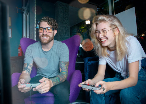 Man and women playing Nintendo Classic while yellow and blue light lenses lenses
