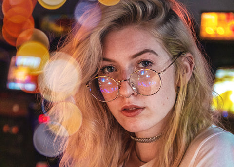 Blonde haired women wearing blue light lenses in a arcade with bokeh in the picture